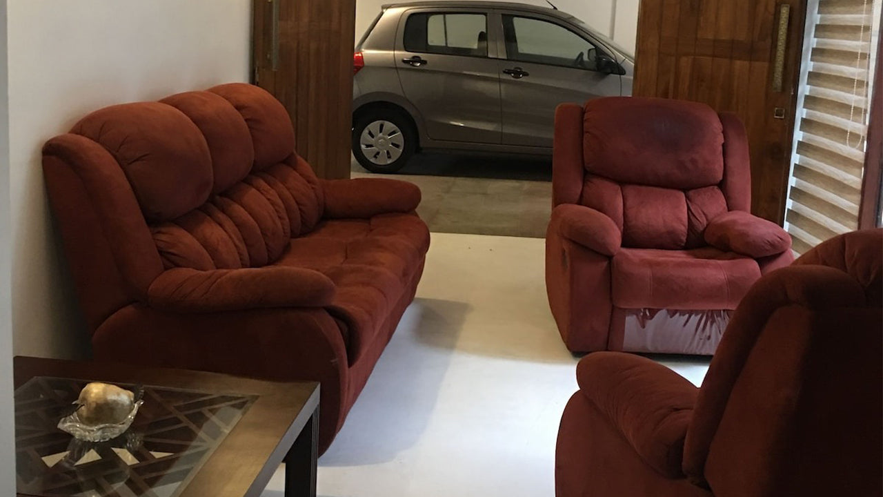 Red sofa and armchair in a room with a car visible through an open door.