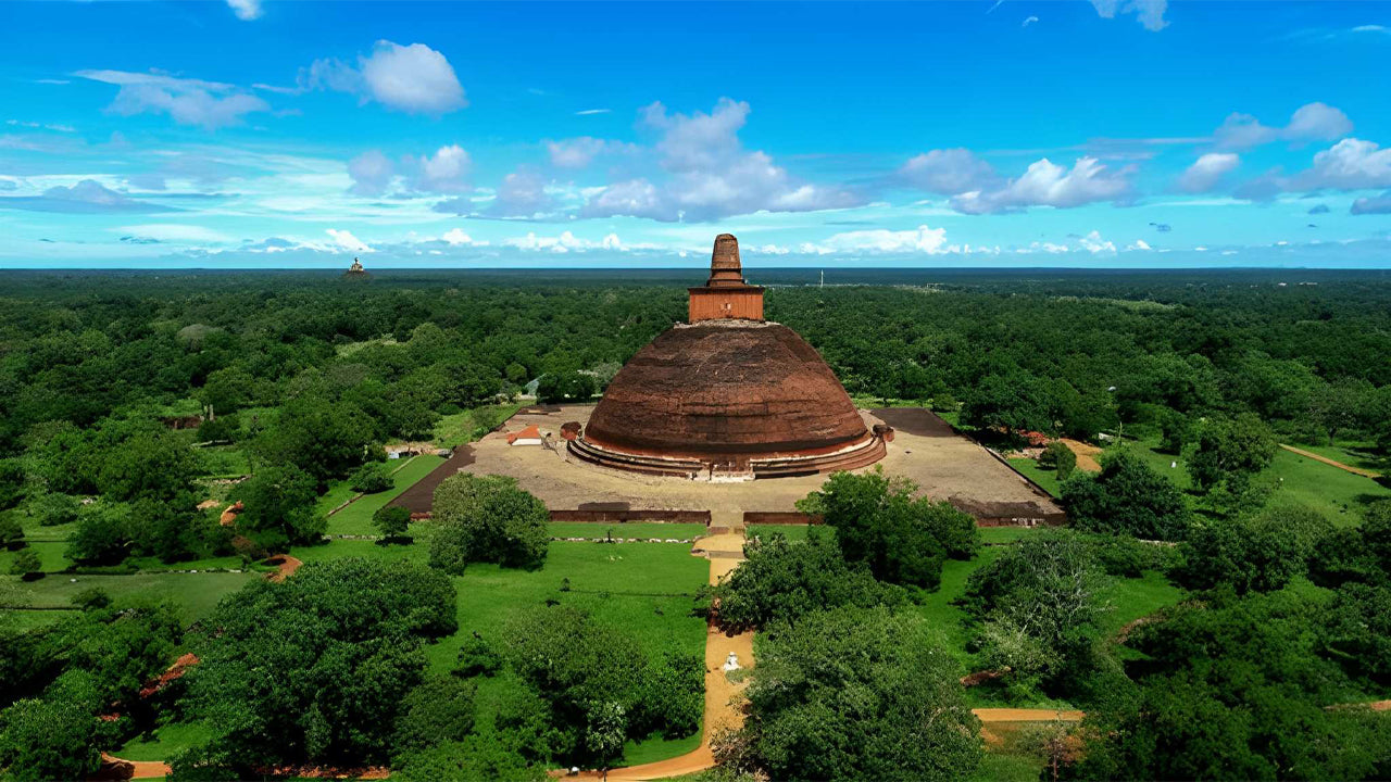 A large stupa surrounded by greenery under a blue sky with scattered clouds.
