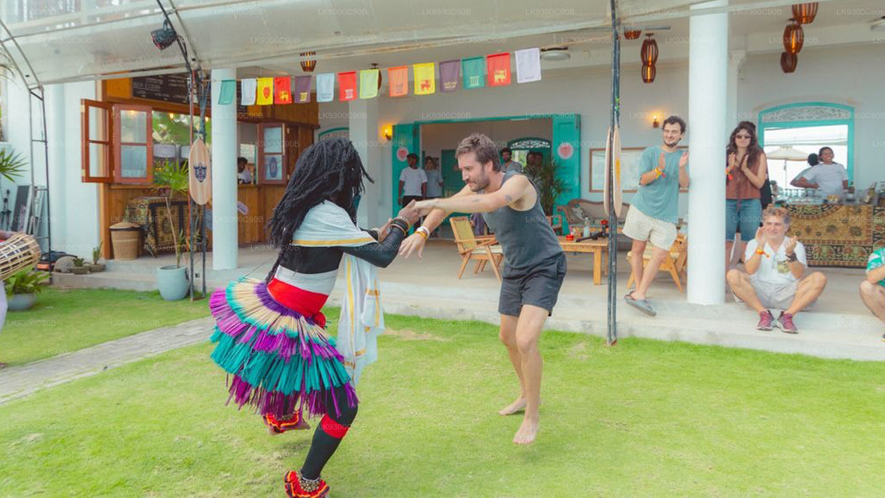 Two people interacting on a grassy area with a building and people in the background