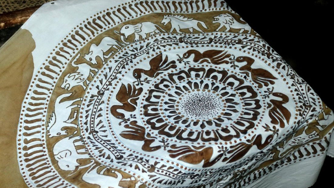 A close-up of a traditional batik fabric with geometric and floral patterns, predominantly in brown and beige tones, showcasing intricate detailing.