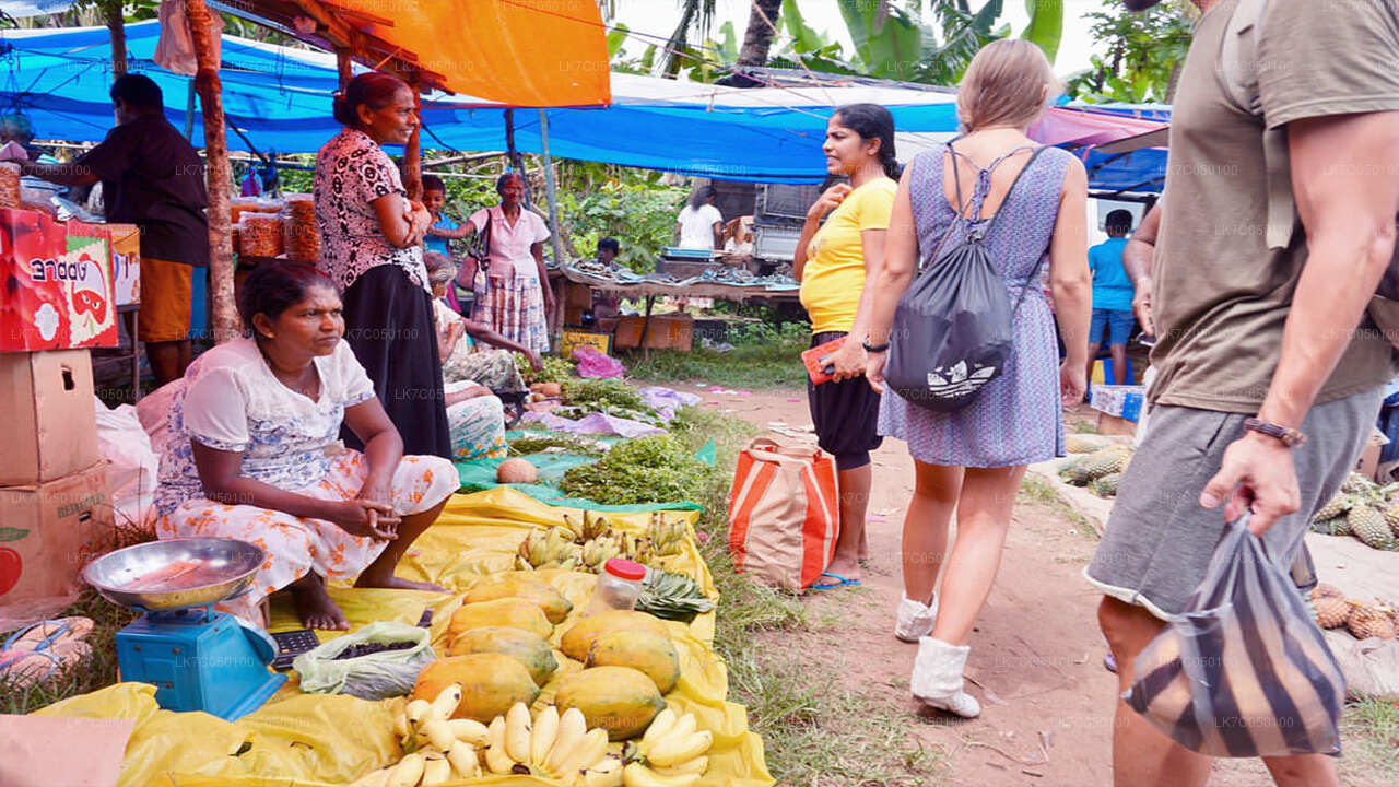 Local Sri Lankan vegetable market scene with tourists walking past fresh produce stalls.